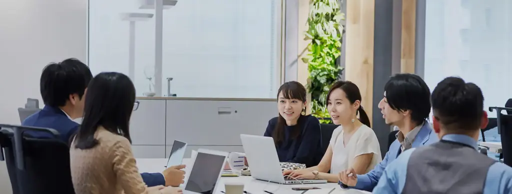 明るいオフィスでミーティングを行うビジネスチームの写真（協働と信頼を重視する企業のイメージ）